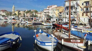 A marina with various boats docked, a prominent church tower in the background, and buildings lining the waterfront. - Villa De luxe -air-conditioned-pool-14 persons, 7 bedrooms and 7 bathrooms, 11 beds (Sanary-sur-Mer)