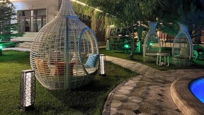 A garden with a large decorative metal structure, seating areas, and a pathway. - ZimaLeto (Yusufhona)