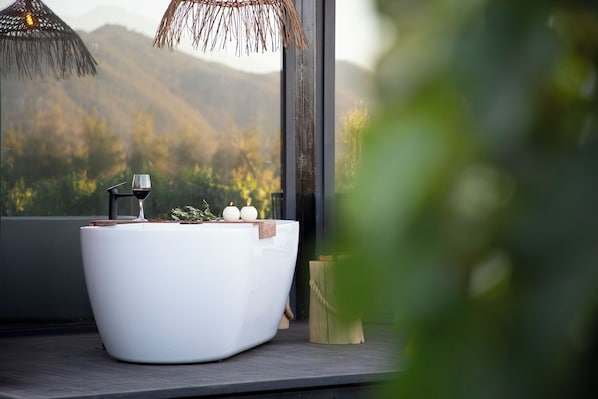 A modern bathroom with a freestanding bathtub, a wine glass, and candles. - Vibo Wine Lodge (Santa Cruz)
