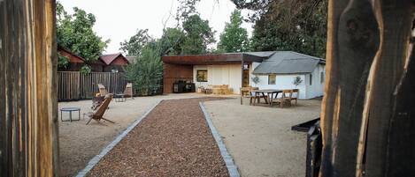 A backyard with a wooden deck, a barbecue grill, and outdoor furniture.