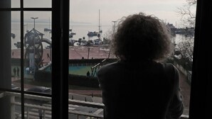 A person standing by a window overlooking a waterfront area with boats and a playground. - Marrakesch Hotel Tuzla (Tuzla)