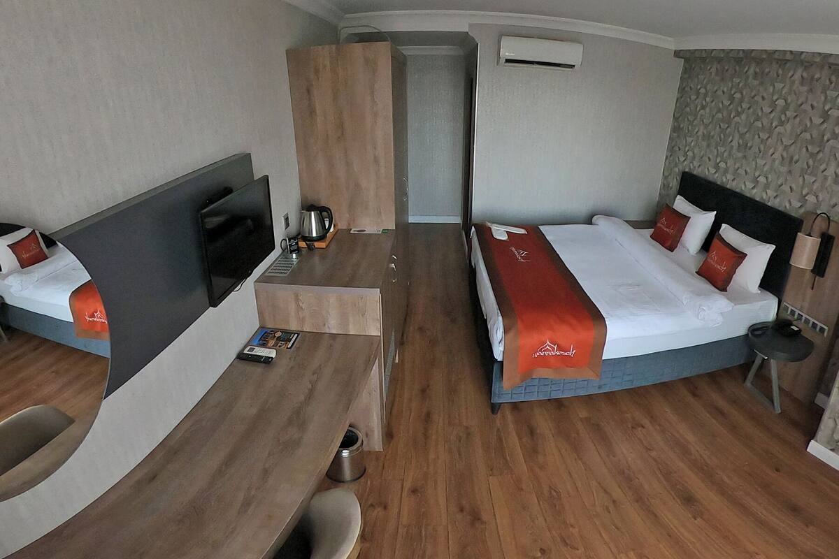 Une chambre d’hôtel moderne équipée de deux lits, d’un bureau et d’un coin salon.