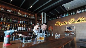 A bar with a variety of liquor bottles on shelves and a counter with a cigar and a glass. - Marrakesch Hotel Tuzla (Tuzla)