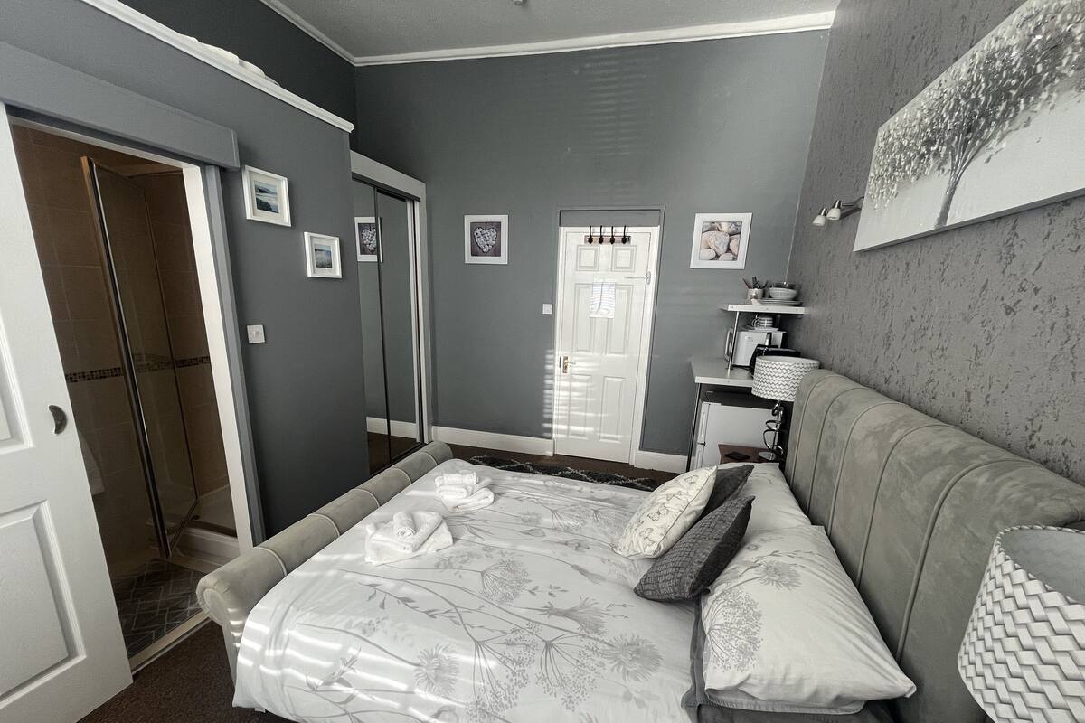 Ein Schlafzimmer mit Bett, einer Couch, einem Schreibtisch und einem Kleiderschrank.