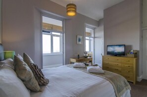 A bedroom with a large bed, a television, a dresser, and a window. - The Buccaneer Inn (Torquay)