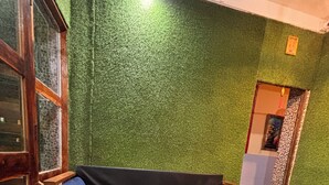 Ein Zimmer mit einer Wand aus grünem Kunstgrün, einem schwarzen Sofa mit floralen Mustern und einem Marmorboden.