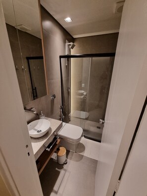 A modern bathroom with a glass-enclosed shower, a sink, and a toilet.