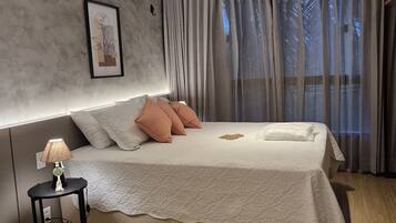 Ein modernes Schlafzimmer mit einem großen Bett, einem Nachttisch mit Lampe und einem gerahmten Bild an der Wand.