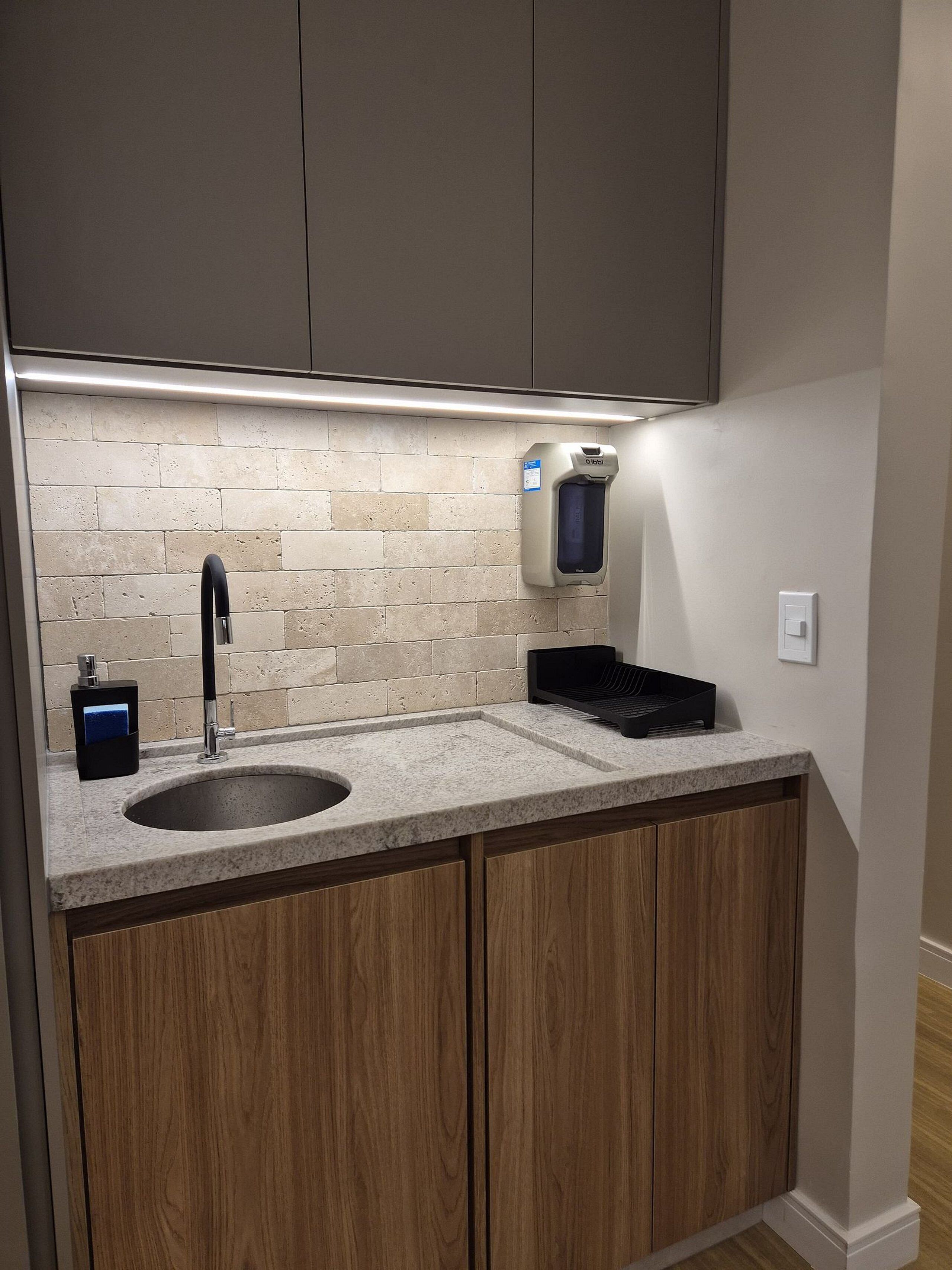 A kitchen with a granite countertop, a sink, and wooden cabinets.