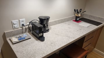 A kitchen with a coffee maker, a sink, and a countertop with a few items.