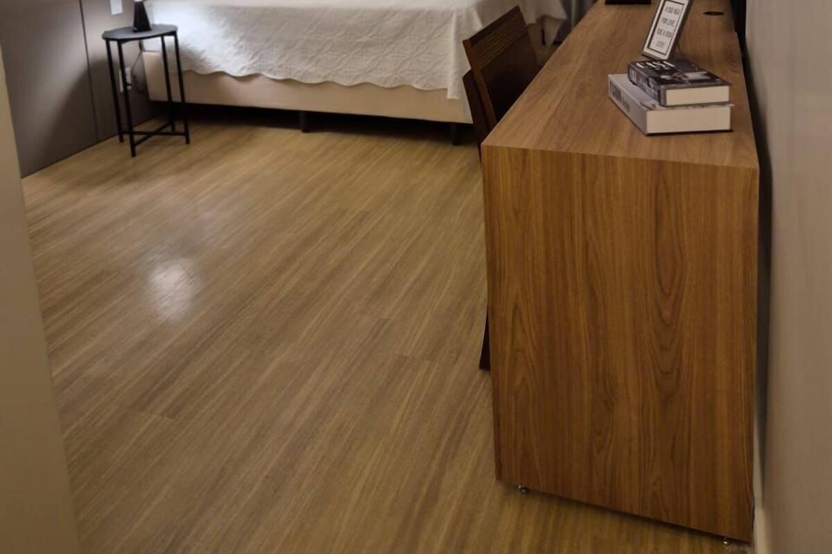 Moderni hotellihuone, jossa on sänky, yöpöytä ja kirjoja sisältävä työpöytä.