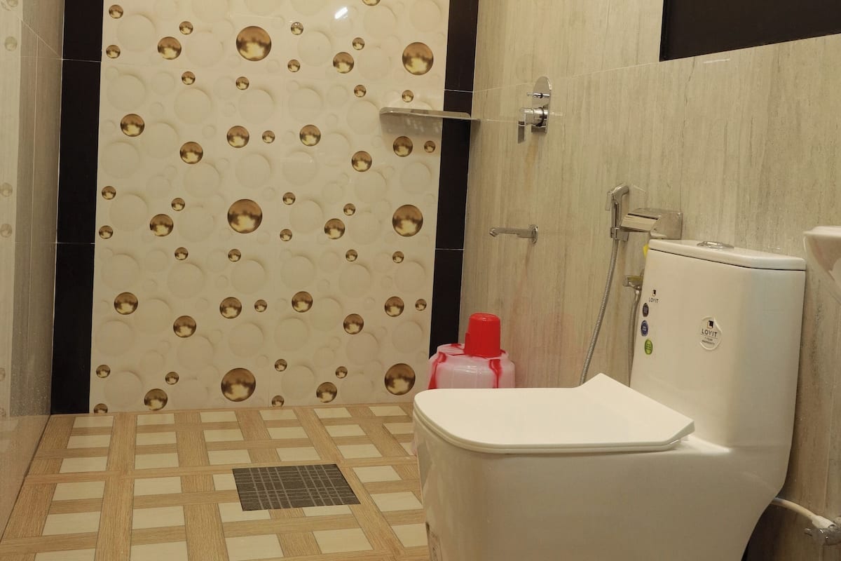 A bathroom with a toilet, shower, and tiled floor.