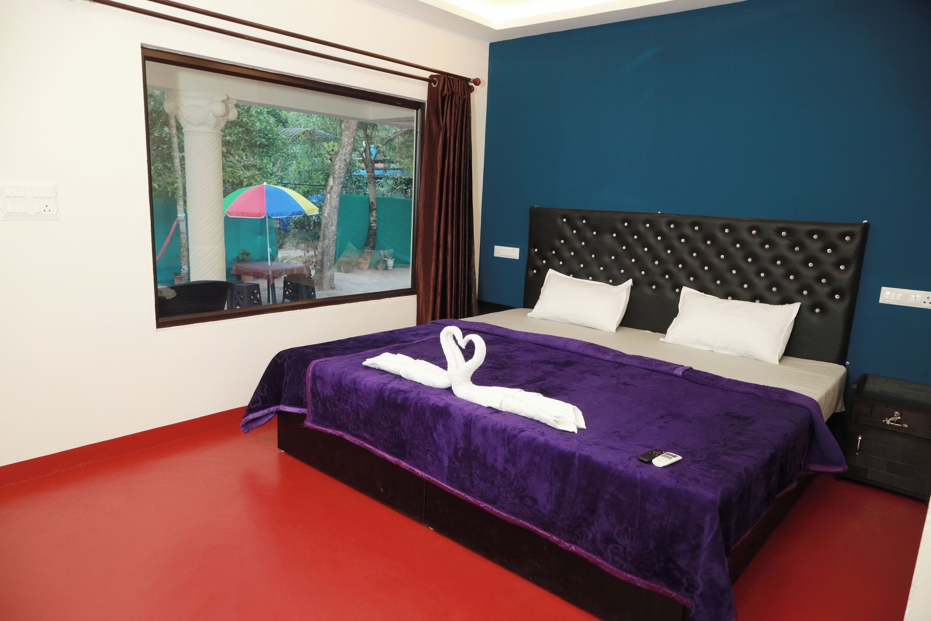 Habitación de hotel con una cama grande, una ventana con vistas al exterior y un suelo rojo.