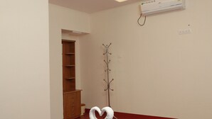 Hotellihuone, jossa on violetti sängynpeite, kattotuuletin, ilmastointilaite ja puinen vaatekaappi.