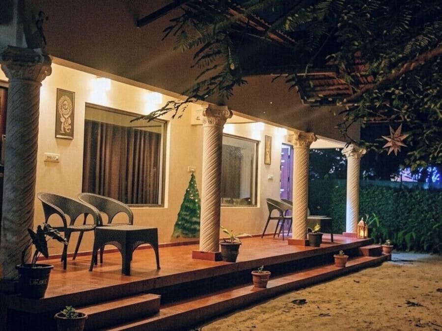 A covered outdoor area with a wooden deck, potted plants, and a Christmas tree.