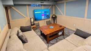 A cozy room with a large flat-screen TV mounted on the wall, a wooden coffee table, and a sectional sofa with cushions. - Inground Pool w/ Fully fenced Yard/ Arcade/  6 beds incl Tri-Bunk/ Theatre  (Wyoming)