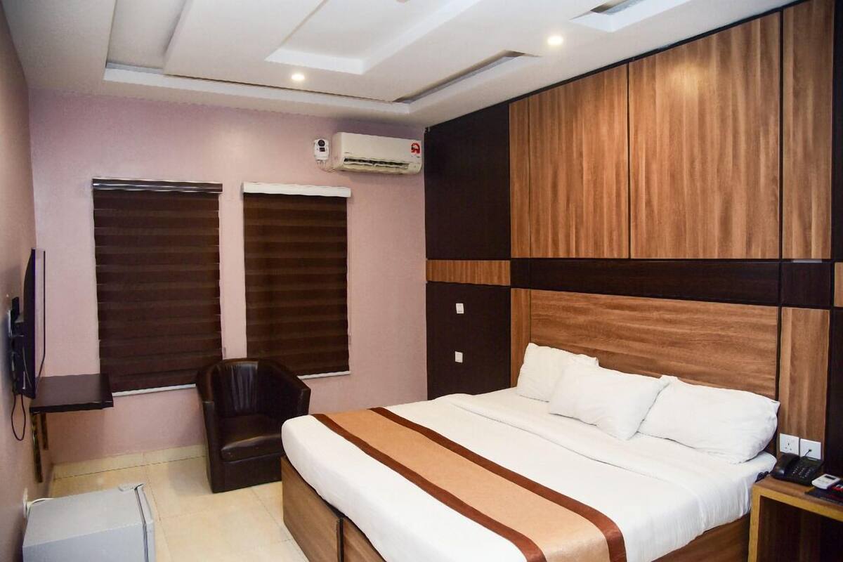 Une chambre d’hôtel avec un grand lit, un bureau, une chaise et un appareil de climatisation.