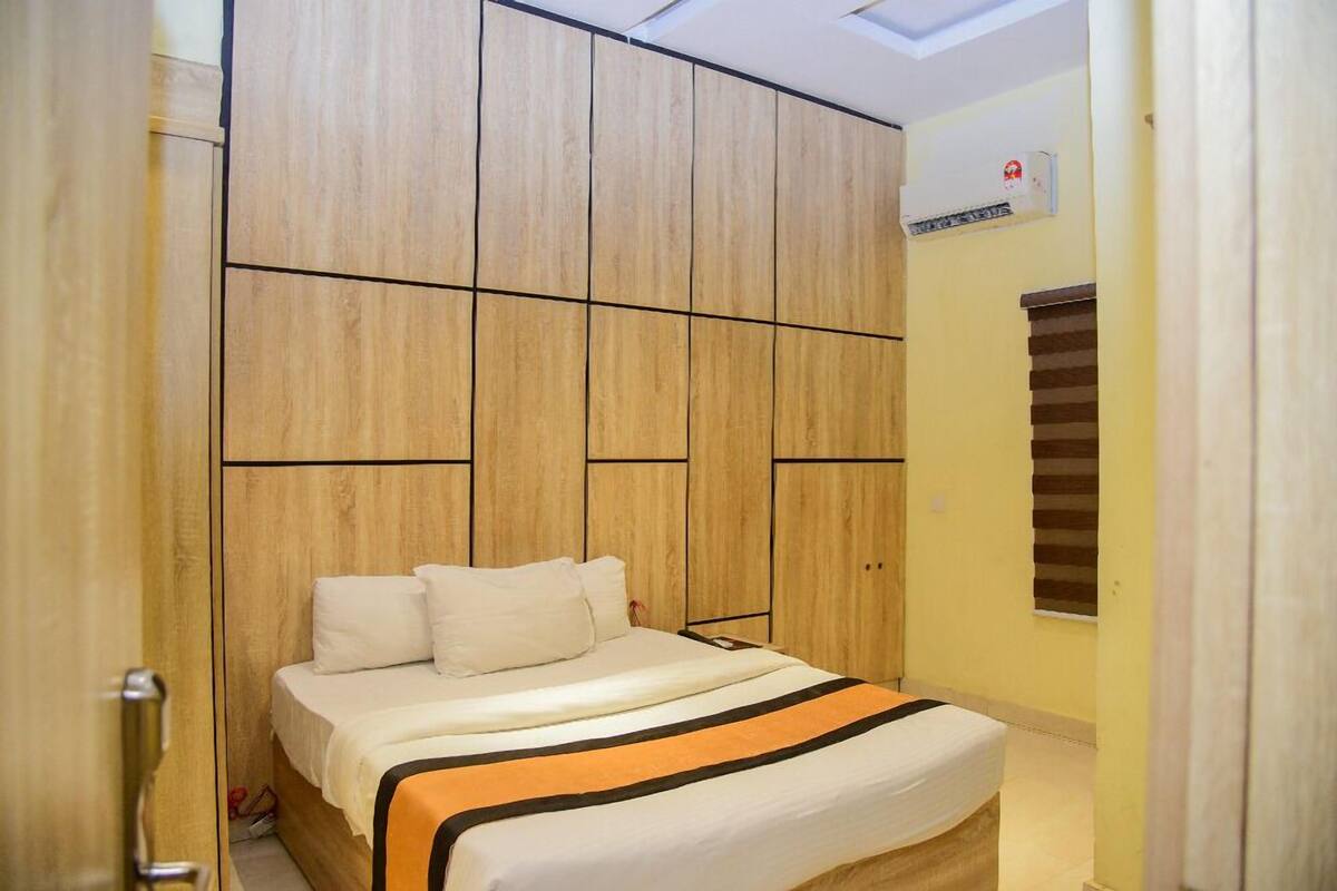 Une chambre à coucher avec un lit, une armoire en bois et une fenêtre avec des stores.