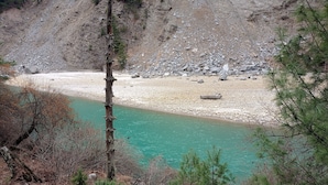 Un paysage naturel caractérisé par une rivière, un terrain rocheux et une végétation clairsemée.