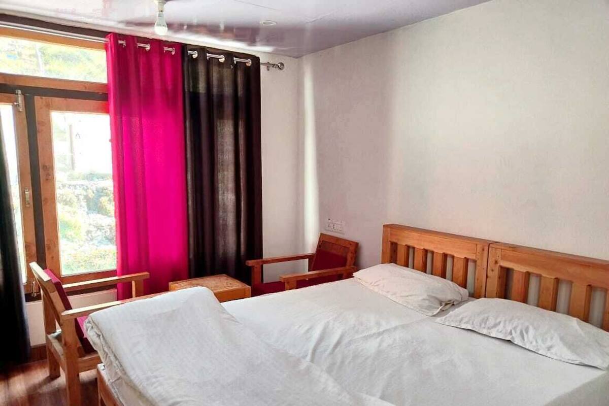 Une pièce avec un lit, une chaise et une fenêtre avec des rideaux.