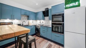 Eine moderne Küche mit blauen Schränken, einem Bosch-Kühlschrank, einem Einbauofen und einer Waschmaschine.