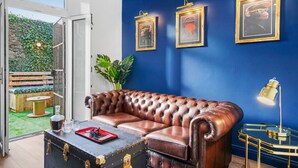 Ein Zimmer mit einer Ledersofa, einer blauen Wand und gerahmten Bildern.