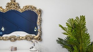 Ein Badezimmer-Waschtisch mit weißer Arbeitsplatte, einem weißen Telefon und einem dekorativen Spiegel mit aufwendigem Goldrahmen.