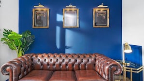 Ein braunes Ledersofa vor einer blauen Wand mit drei gerahmten Bildern.