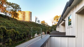 Un bâtiment moderne doté d’un balcon donnant sur une route et une colline.