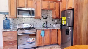A kitchen with wooden cabinets, a stainless steel refrigerator, a microwave, a stove, and a water dispenser. - Cloud 9 - new ocean view house in La Boca with WiFi, AC (La Boca)