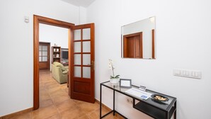 A hallway with a wooden door, a glass desk with a laptop, a potted plant, and a framed certificate. - Casa Morro Blanco - Four Bedroom Villa, Sleeps 8 (Conil)