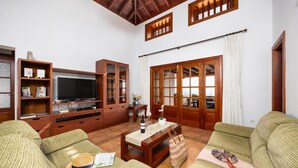 A living room with a TV, wooden cabinets, and two green sofas. - Casa Morro Blanco - Four Bedroom Villa, Sleeps 8 (Conil)