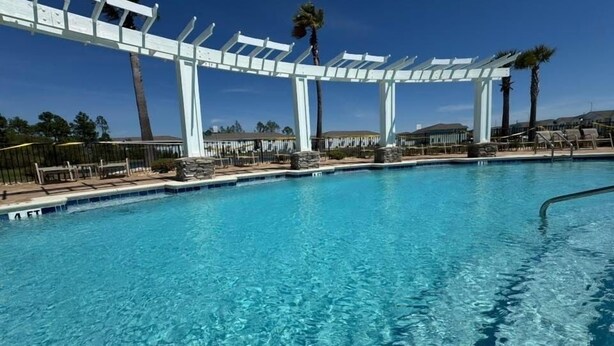 A clear blue pool with white pergolas and palm trees in the background. - Winter monthly rates 3000 fully furnished  (Panama City Beach)