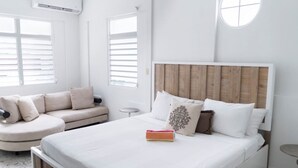 Ein modernes Schlafzimmer mit einem großen Bett, einer Couch und einem runden Fenster.