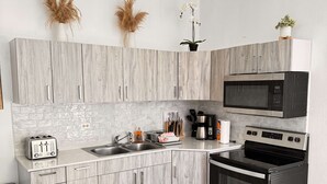 Eine moderne Küche mit grauen Holzschränken, einer Edelstahl-Mikrowelle, einem schwarzen Backofen und einer weißen Arbeitsplatte.