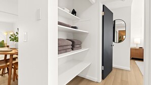 A modern interior with white walls, a wooden dining table, and a black door with a mirror. - New! Modern 2BR by Downtown Royal Oak | King Beds (Royal Oak)