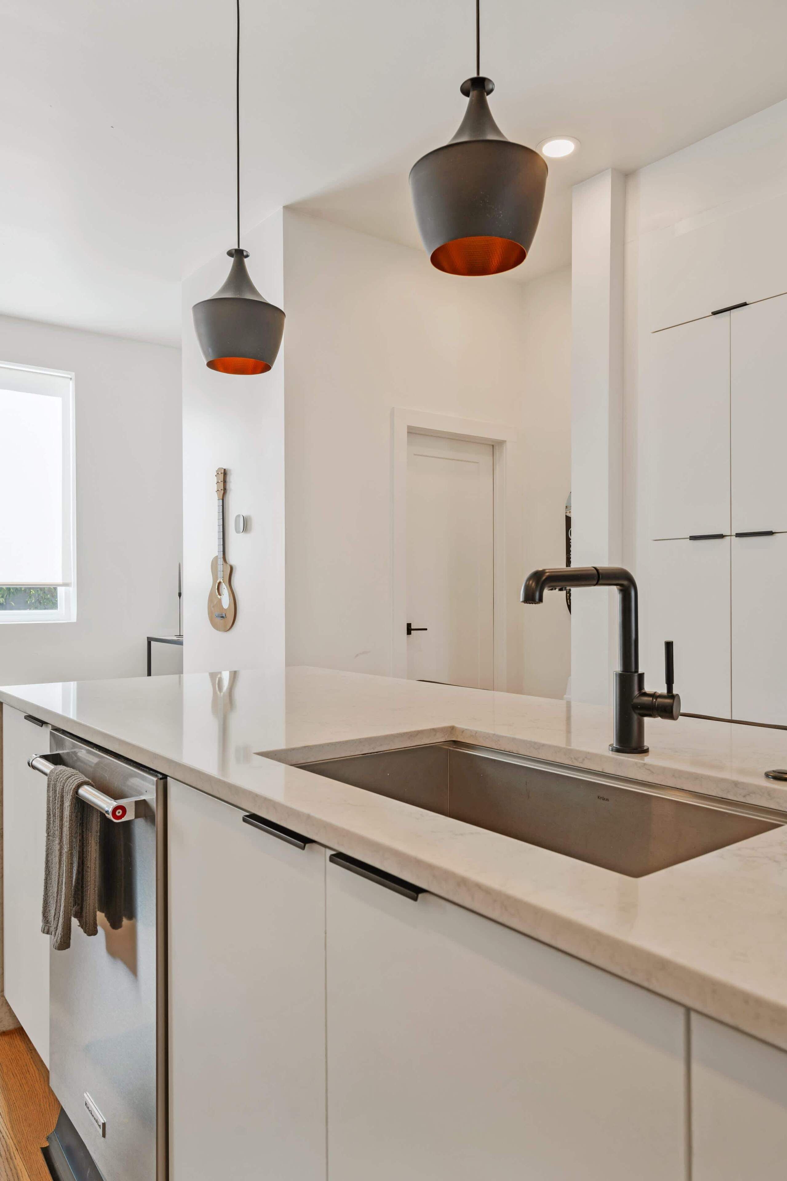 Cozinha moderna com ilha grande, eletrodomésticos de aço inoxidável e iluminação pendente.