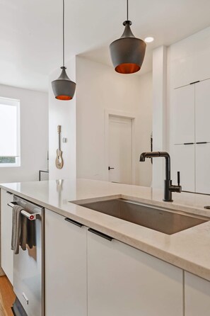 Una cocina moderna con una isla grande, electrodomésticos de acero inoxidable e iluminación colgante.