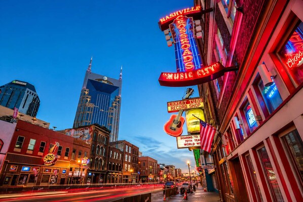A city street with neon signs, including one for a record shop and another for a music city.