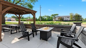 Une terrasse extérieure avec des chaises et des tables en bois, un foyer et un espace salon abrité.