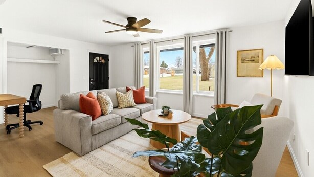Un salon moderne avec un canapé gris, une table basse ronde et un ventilateur de plafond.