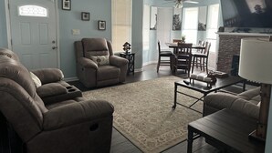 A living room with a recliner, a dining table with chairs, a fireplace, and a TV.