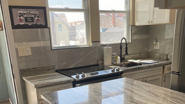 A kitchen with a large island, white cabinets, and a window overlooking the neighborhood.