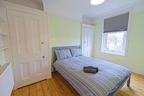 Ein Schlafzimmer mit Bett, Kleiderschrank und einem Fenster mit Jalousien.