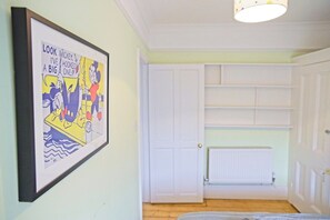 Una habitación con un dibujo animado enmarcado en la pared, una puerta blanca y un radiador.