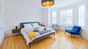 A bedroom with a bed, a chair, a nightstand, and a window.