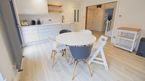 A modern kitchen with white cabinetry, a round dining table, and a small seating area.