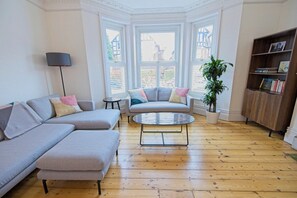 Un salón con un sofá seccional, una mesa de centro redonda y una estantería.