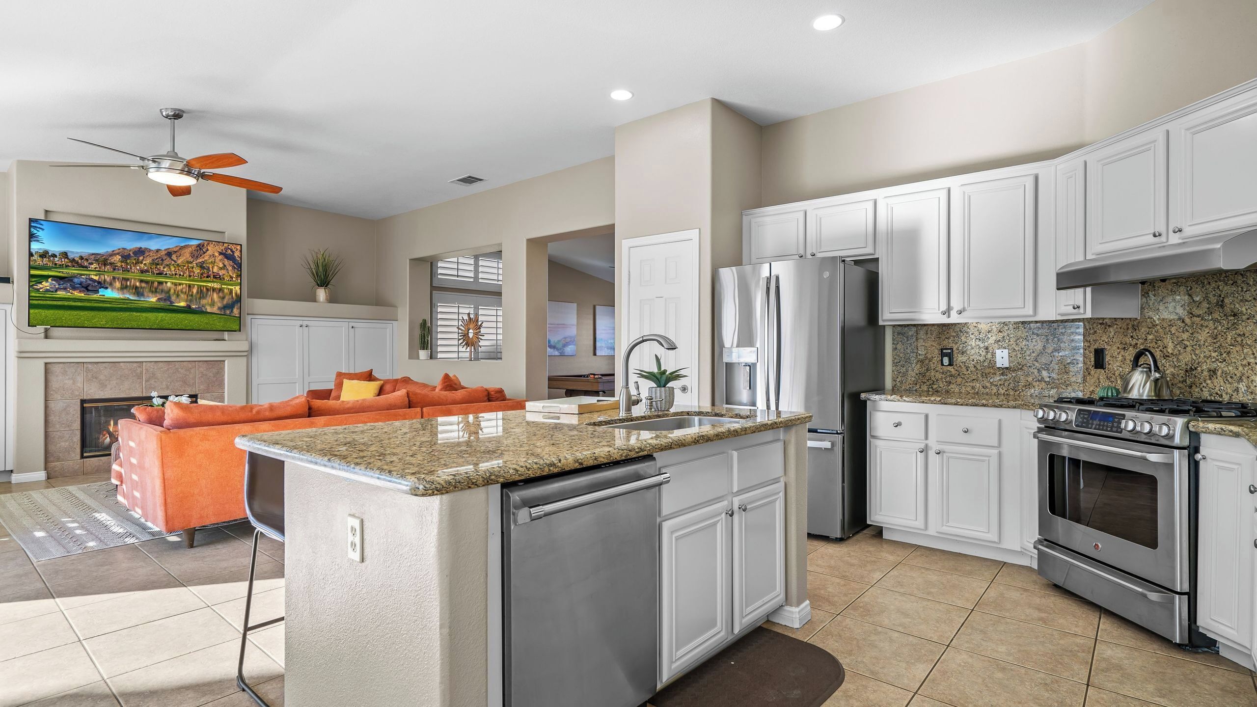 A modern kitchen with granite countertops, stainless steel appliances, and white cabinetry.