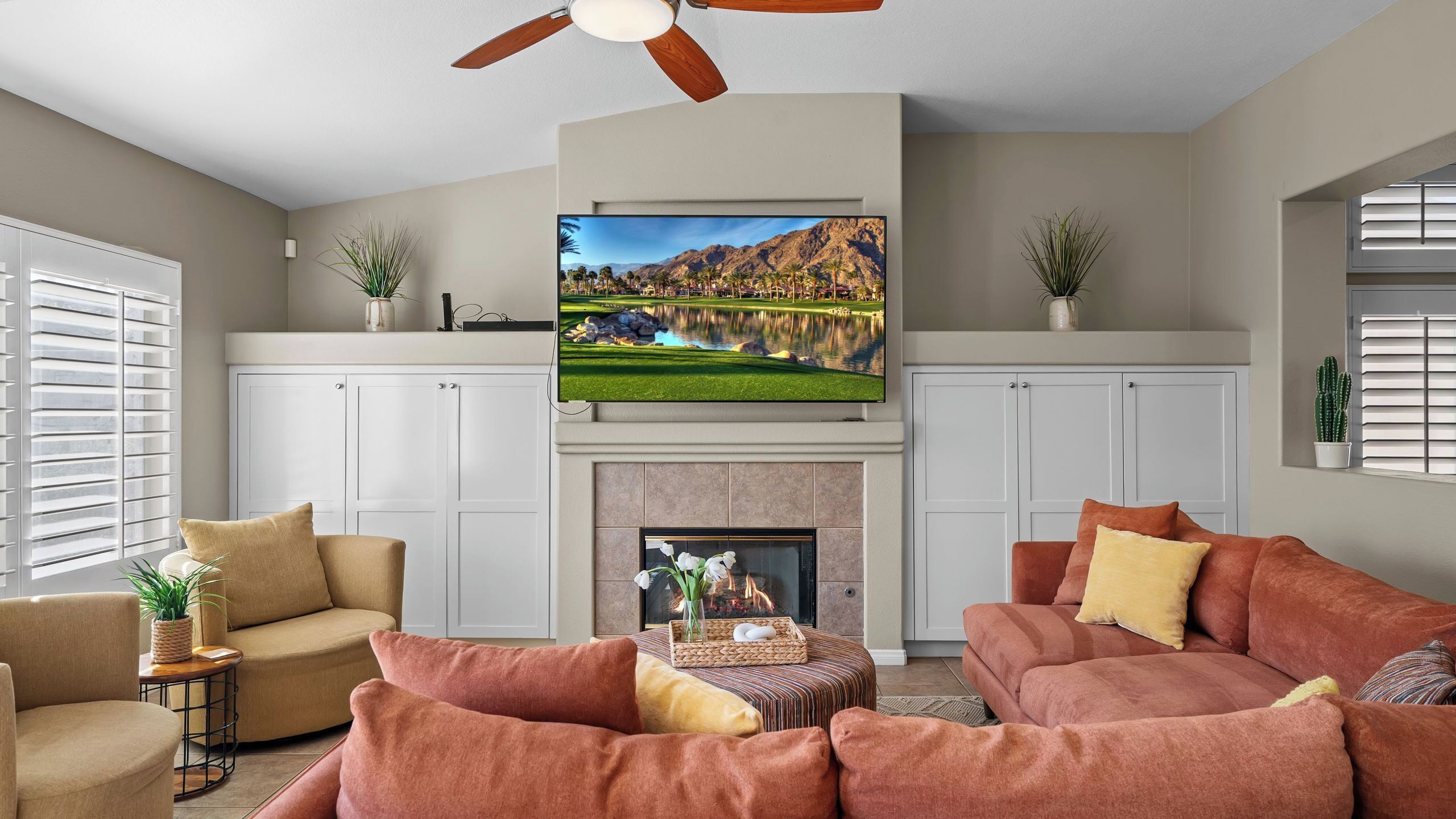 A living room with a fireplace, a television mounted above it, and two sofas.
